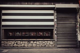 Front of a shop with its iron curtain almost closed