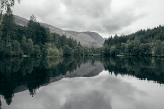 Landscape of a lake surrounded by woods under a threatening sky