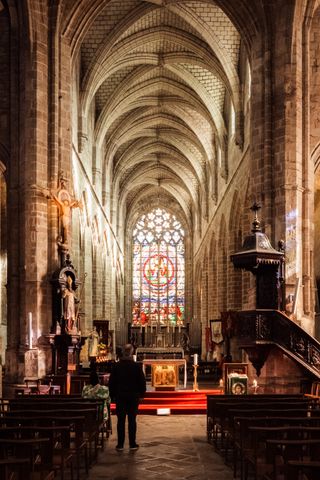 Two people in an empty glowing church facing the altar while praying