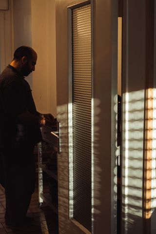 A man doing some cooking behind the door of the kitchen with rays of light on it