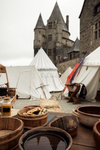 Medieval table with wooden bowl and food before tents and a castle