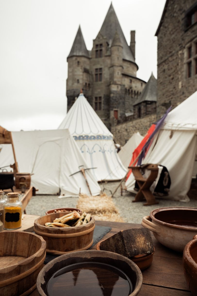 Medieval table with wooden bowl and food before tents and a castle