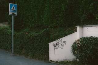A sidewalk with a small white wall with a graffiti
