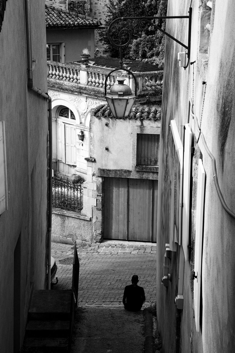 Narrow street in an old town, viewed from a higher standpoint, with a person sitting at the crossroads