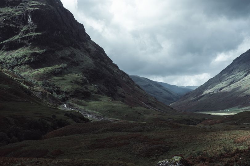 Wild valley between moutains with a water stream going down of the first mountain.