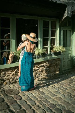 A mother holding and lifting her child for them to see a shop showcase