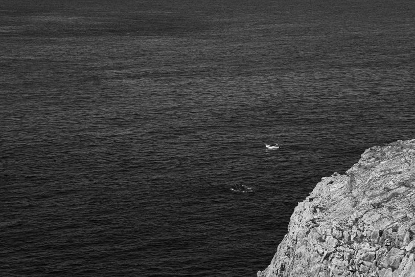 A small boat in the great sea leaving the coast