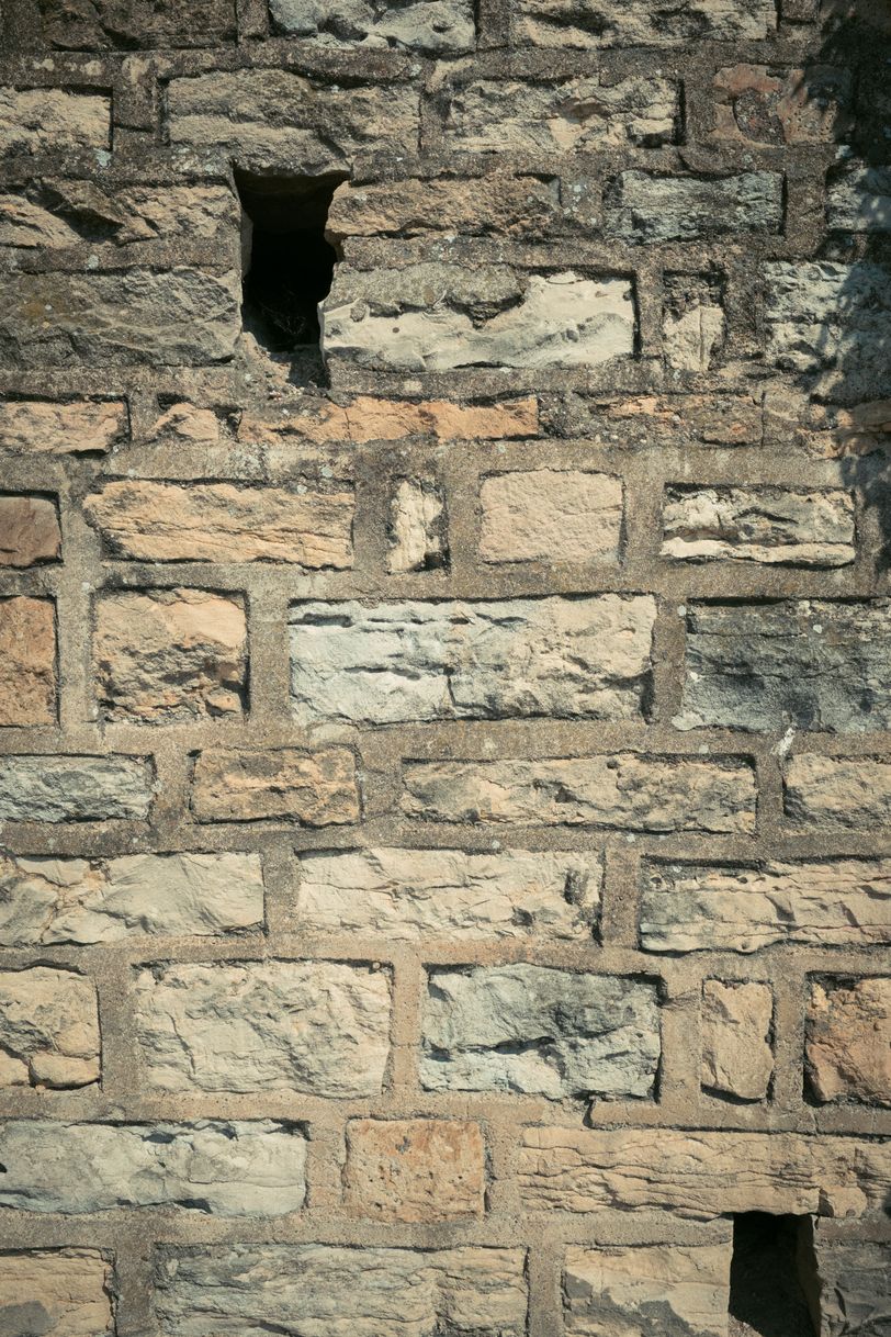 Close up on a stone wall with holes in it