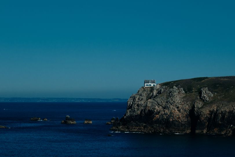 A white house at the edge of a cliff facing the sea