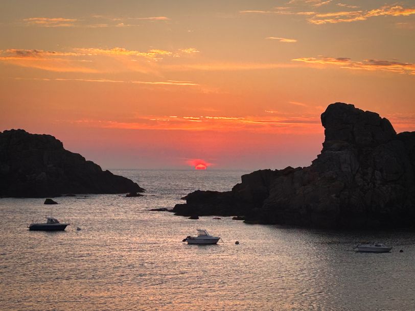 Sunset on a rocky bay with three moored boats