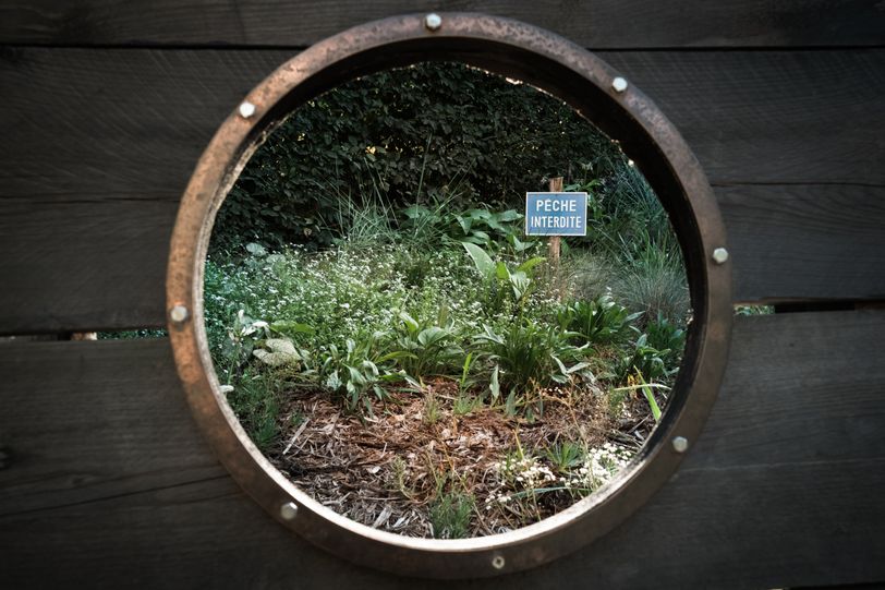 View from a porthole of a garden with a sign saying no fishing