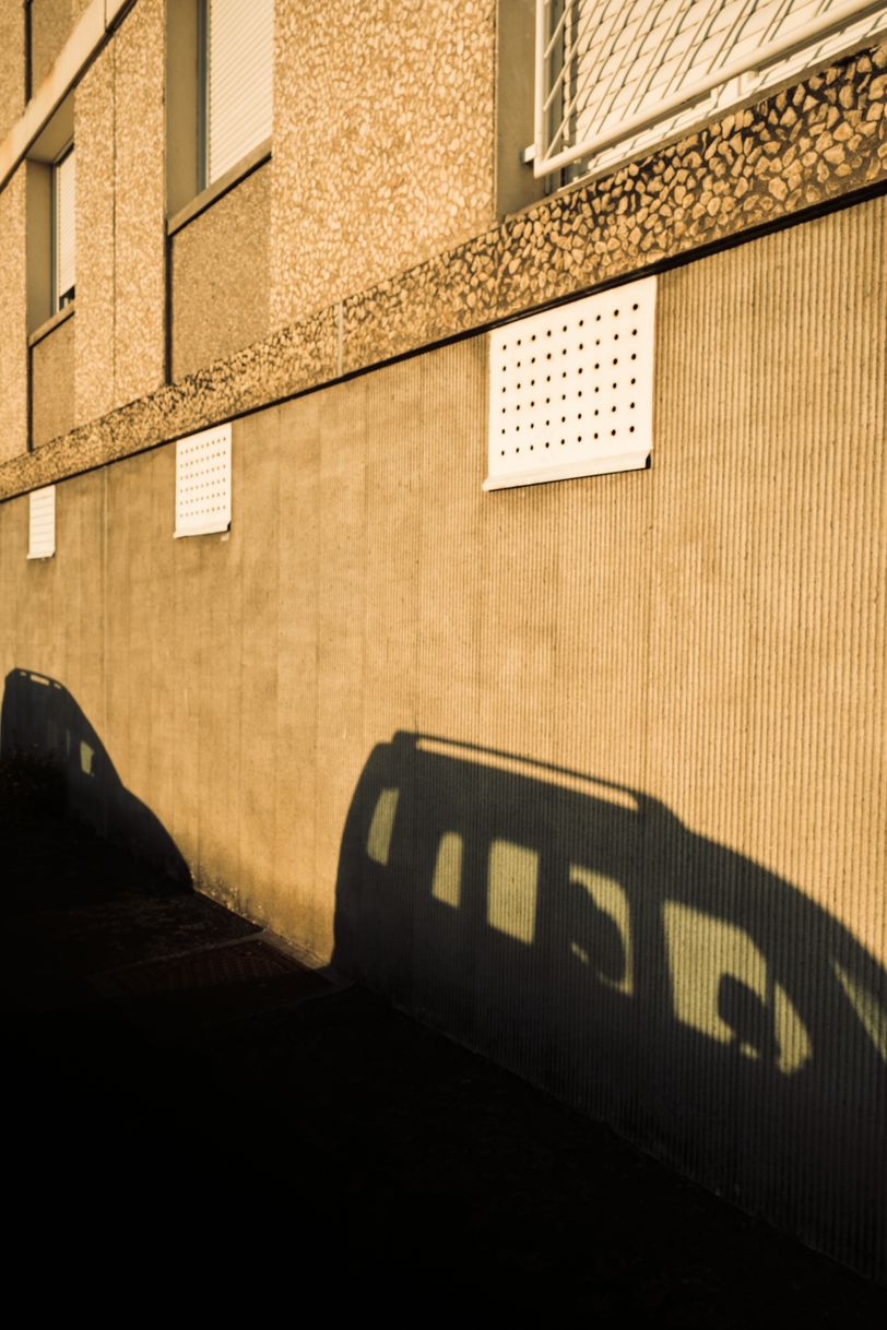 Shadows of cars on a building wall at sunset