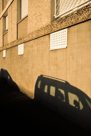 Shadows of cars on a building wall at sunset