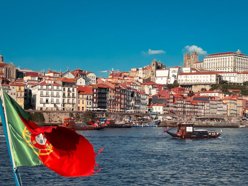 Cityscape of Porto with a portuguese flag in the foreground