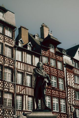 A statue of Jean Leperdit before a series of old houses