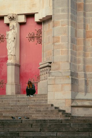 A young woman sitting on the stairs of a closed church