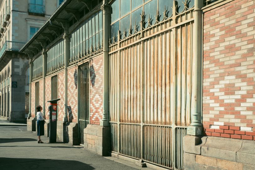 A woman standing straight in front of a meter in the street
