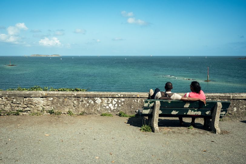 A couple sitted on a bench watching the sea