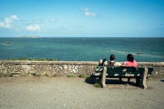 A couple sitted on a bench watching the sea