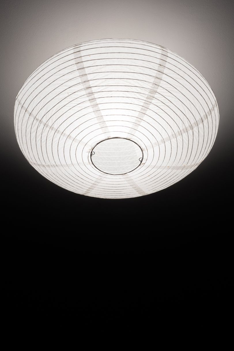 Round lampshade with the light on on a white ceiling