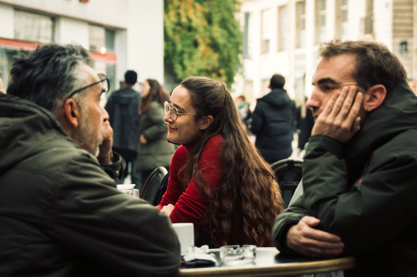 Bunch of people outside a cafe having discussions and a woman enjoying her time in the middle