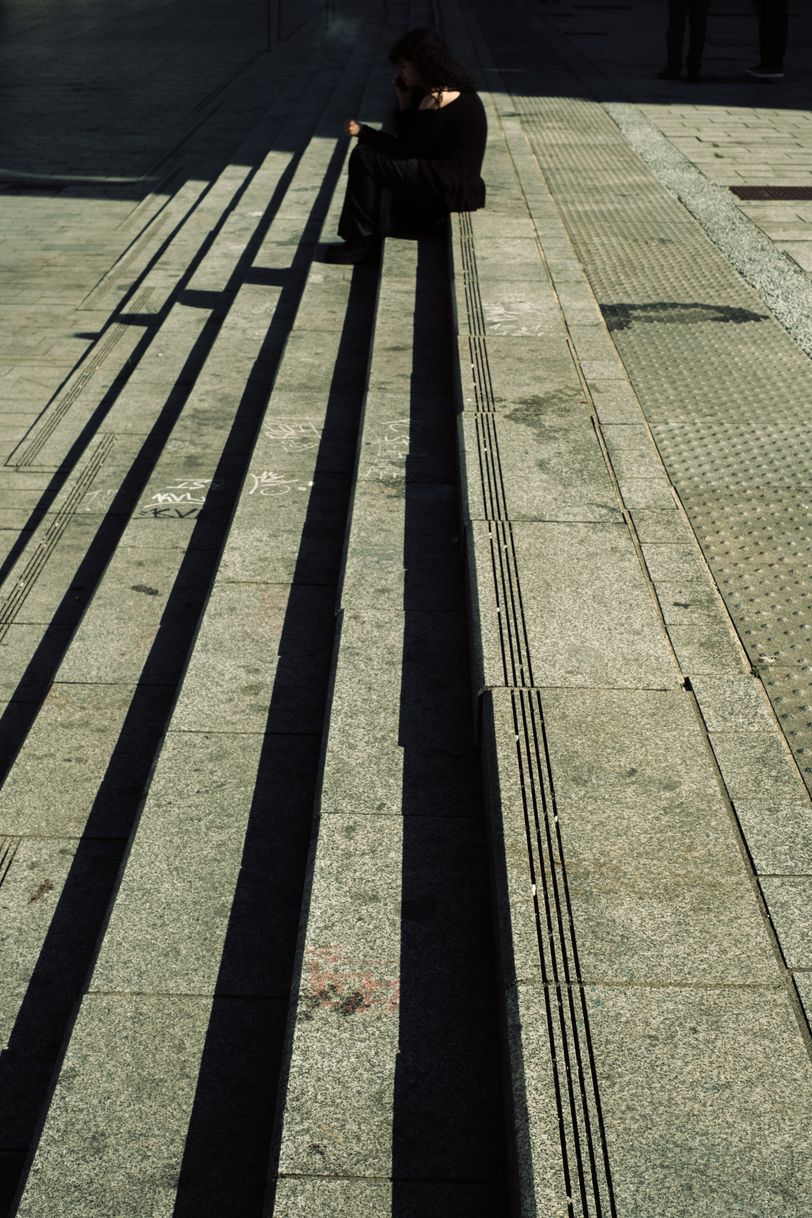 A young woman smoking a cigarette while sitting on stairs on a public place