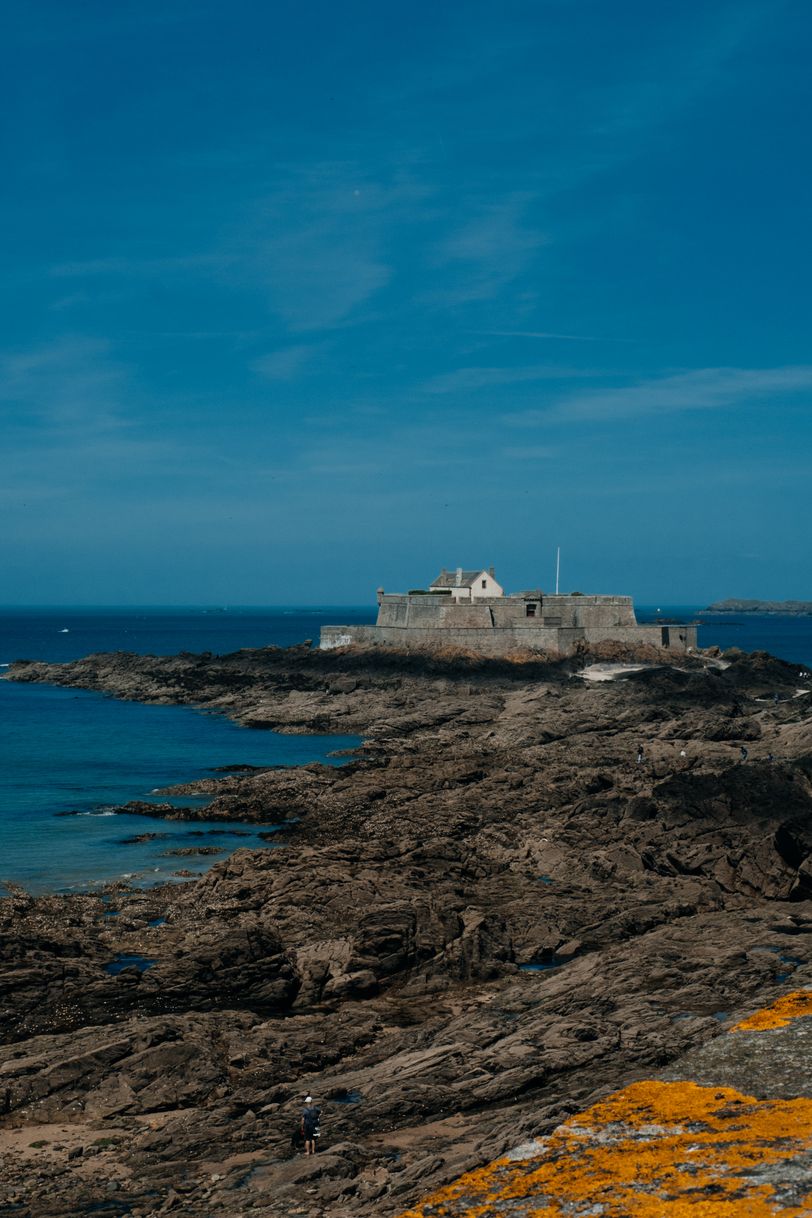 Fortified house on the shore and a single person hiking there