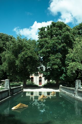 Three golden miniatures boats in a pond before a mansion