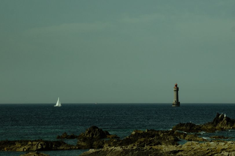 A sailboat meeting a lighthouse at sea