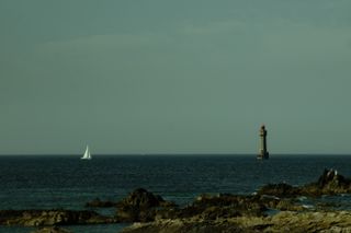 A sailboat meeting a lighthouse at sea