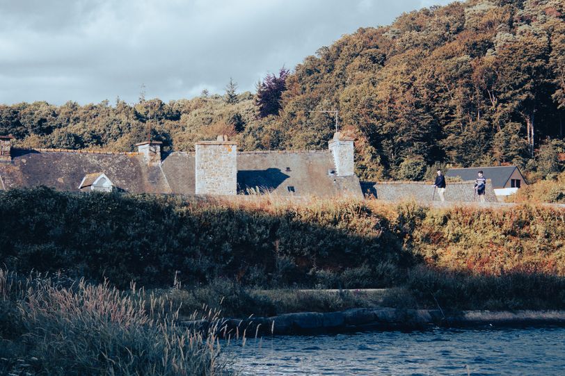 People walking on an elevated footpath, it looks like theya re actually walking on the roofs of the house behind