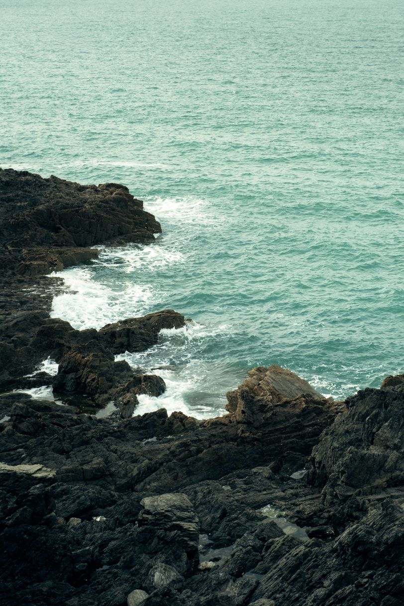 Coast of black rocks and light blue sea